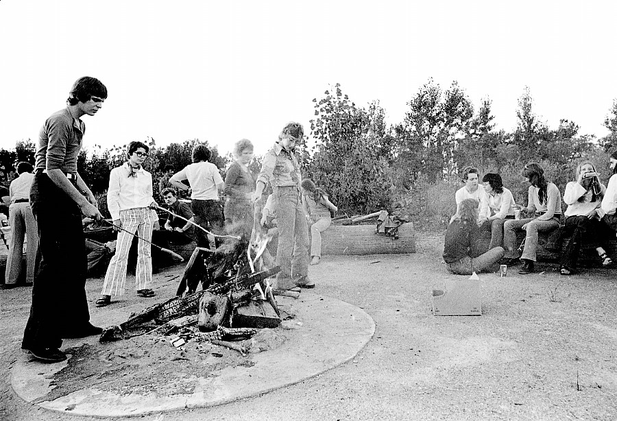 a few people gathered around the bonfire at the 1972 picnic